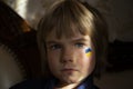 Unhappy face of a boy from Ukraine with a painted yellow-blue heart on his cheek, highlighted with a strip of light Royalty Free Stock Photo