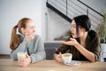 Unhappy female friends discuss shocking news. Two shocked young women covering mouth and looking at each other at cafe Royalty Free Stock Photo