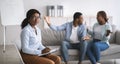 Unhappy female psychologist and black married couple having fight during session at office, copy space Royalty Free Stock Photo