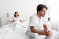 Unhappy frustration european young man ignoring angry woman, lady sits in bed and scream on guy in white bedroom Royalty Free Stock Photo
