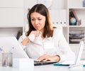 Unhappy girl holding napkin during work with laptop and documents Royalty Free Stock Photo