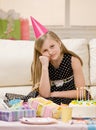 Unhappy girl in party hat sits with gifts