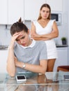 Unhappy girl sitting at table after quarrel, woman friend on backround