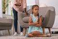 Unhappy gloomy little girl sitting cross handed