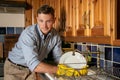 Unhappy handsome young man washing dishes in kitchen