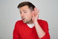 Unhappy hard of hearing man placing hand on ear asking someone to speak up Royalty Free Stock Photo