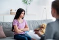 Unhappy Indian teen girl having session with psychologist at clinic, sitting with crossed arms, thinking about problems Royalty Free Stock Photo
