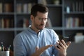 Unhappy irritated man wearing glasses having problem with smartphone Royalty Free Stock Photo