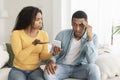 Unhappy jealous angry young african american wife show smartphone to sad confused husband accuses of treason Royalty Free Stock Photo