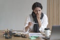 Unhappy latin business woman dressed in warm scarf checking body temperature at work