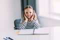 Unhappy little Caucasian girl child sit at table at home feel lazy unmotivated doing homework assignment. Upset distressed small Royalty Free Stock Photo