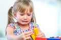 Unhappy little girl playing with wooden blocks. Royalty Free Stock Photo