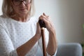 Unhappy lonely mature woman holding walking stick close up