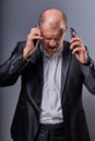 Unhappy loud crying angry business man talking on mobile phone very emotional in office suit on grey background. Closeup Royalty Free Stock Photo