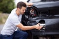 Unhappy Male Driver Inspecting Damaged Car After Accident