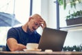 Unhappy man holds head in hand tired businessman sits at work desk with laptop feels headache Royalty Free Stock Photo