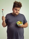 Unhappy, man and salad for diet with healthy food, fork or bowl and vegetables for wellness on studio background. Plus