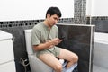 Unhappy man with stomachache using smartphone and sitting in toilet bowl in bathroom at home Royalty Free Stock Photo