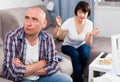 Unhappy mature man after quarrel, woman on background