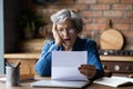 Unhappy mature wearing glasses reading bad news in letter