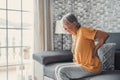 Unhappy mature woman touching back, feeling pain, sitting on couch in living room, unhealthy middle aged senior female suffering Royalty Free Stock Photo