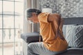 Unhappy mature woman touching back, feeling pain, sitting on couch in living room, unhealthy middle aged senior female suffering Royalty Free Stock Photo