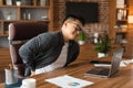 Unhappy middle aged asian man manager in glasses suffering from muscles back pain at table with laptop Royalty Free Stock Photo