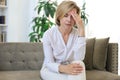 Unhappy middle aged woman sitting on a sofa in the living room Royalty Free Stock Photo