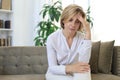 Unhappy middle aged woman sitting on a sofa in the living room Royalty Free Stock Photo