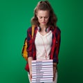 Unhappy modern student woman holding pile of books
