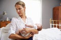 Unhappy Mother Dressed For Work Holding Baby In Bedroom