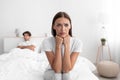 Unhappy offended european young woman sitting on bed turn away from husband, ignoring him in white bedroom Royalty Free Stock Photo