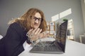 Unhappy office worker sitting at desk chained to laptop computer and unable to go home