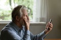 Unhappy old man shocked by news on smartphone