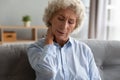 Unhappy older woman massaging tensed neck muscles, feeling unwell