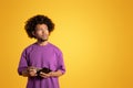 Unhappy pensive black adult curly man in purple t-shirt hold empty wallet, look at free space Royalty Free Stock Photo