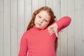 Unhappy redhead preteen girl shows thumb down and expressing dislike