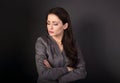 Unhappy resentful business woman in suit with folded arms looking down on dark grey background Royalty Free Stock Photo