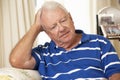 Unhappy Retired Senior Man Sitting On Sofa At Home