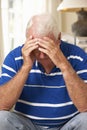 Unhappy Retired Senior Man Sitting On Sofa At Home