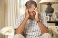 Unhappy Retired Senior Man Sitting On Sofa At Home