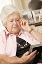 Unhappy Retired Senior Woman Sitting On Sofa At Home Looking At Photograph