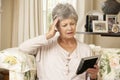 Unhappy Retired Senior Woman Sitting On Sofa At Home Looking At Photograph