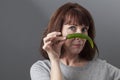 Unhappy 50s mature woman questioning the taste of green pepper Royalty Free Stock Photo