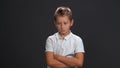 Unhappy or sad little boy looking a side frowning wearing white polo shirt and black pants isolated on black background Royalty Free Stock Photo