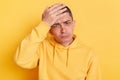 Unhappy sad man wearing casual style hoodie, posing isolated over yellow background, making facepalm gesture, loser, forget about Royalty Free Stock Photo