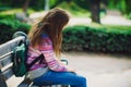 Unhappy and sad schoolgirl sitting on wooden bench in the park Royalty Free Stock Photo