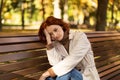 Unhappy sad tired young european red-haired woman in raincoat suffers from headache and pressure alone Royalty Free Stock Photo