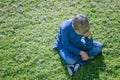 Unhappy sad upset boy sitting alone on the grass Royalty Free Stock Photo