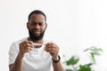 Unhappy sad young black bearded man hold thermometer with high temperature in bedroom Royalty Free Stock Photo